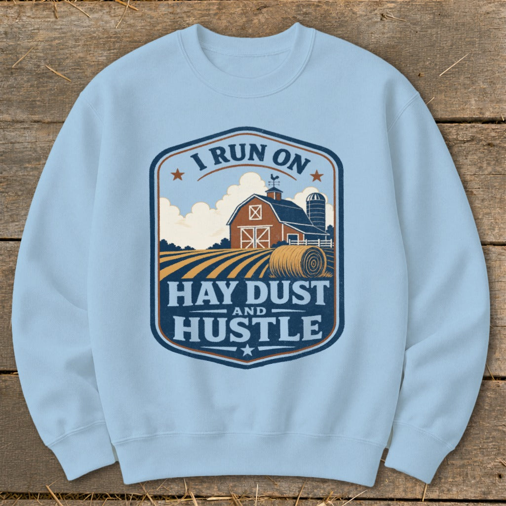 Light blue sweatshirt with a farm graphic that reads "I RUN ON HAY DUST AND HUSTLE."