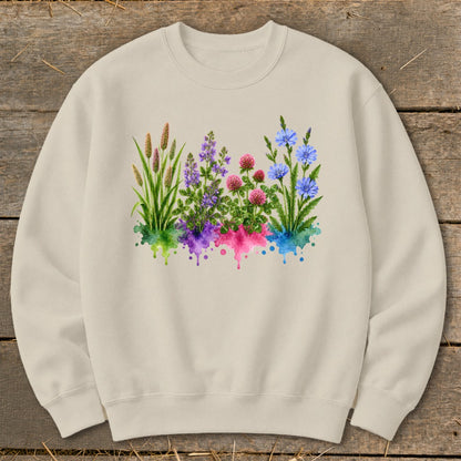 Beige crewneck sweatshirt featuring a watercolor graphic of four distinct wildflower clusters above colorful paint splatters.