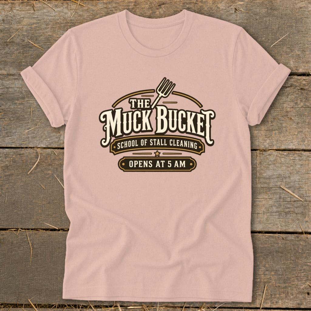 Pink t-shirt with "The Muck Bucket School of Stall Cleaning Opens at 5 AM" graphic.