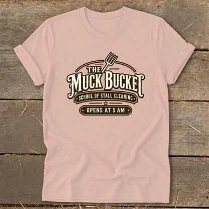 Pink t-shirt with "The Muck Bucket School of Stall Cleaning Opens at 5 AM" graphic.