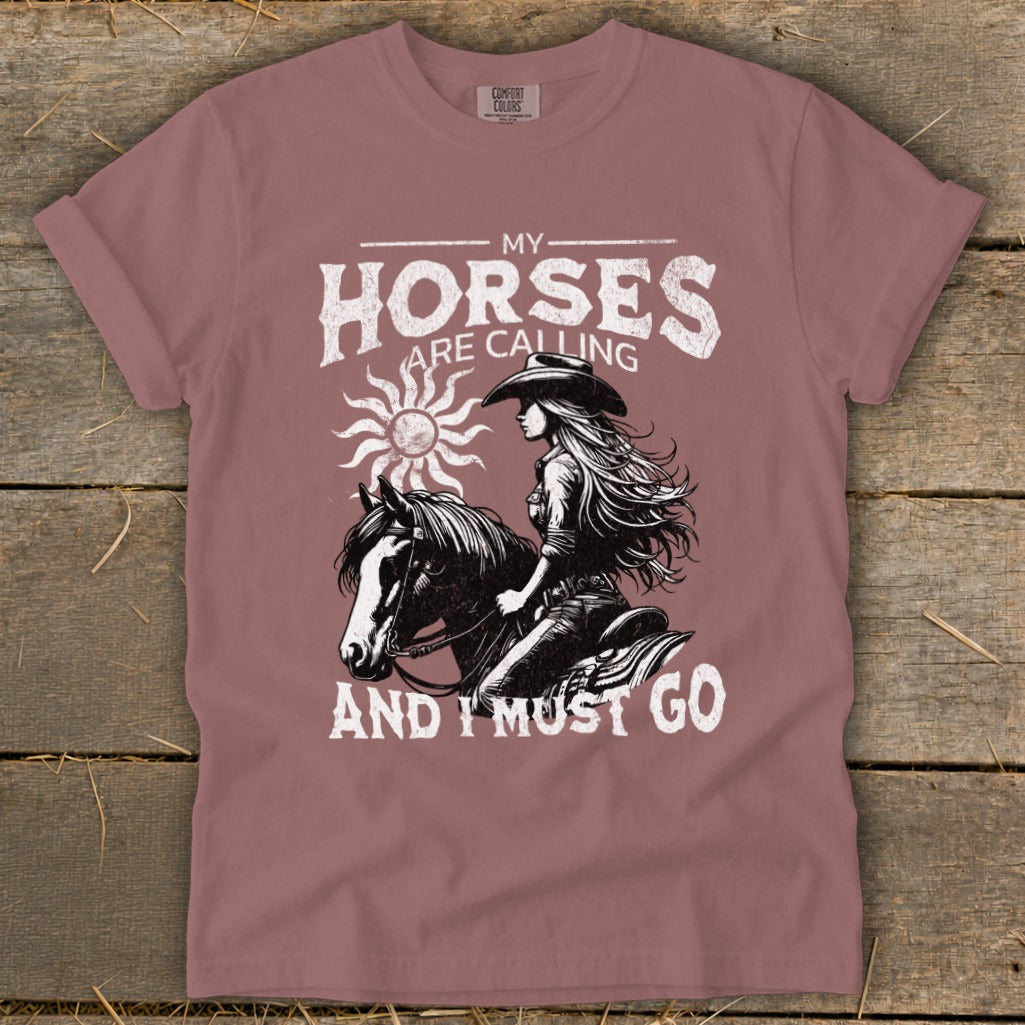 T-shirt graphic with woman on horse and text "My Horses Are Calling And I Must Go".