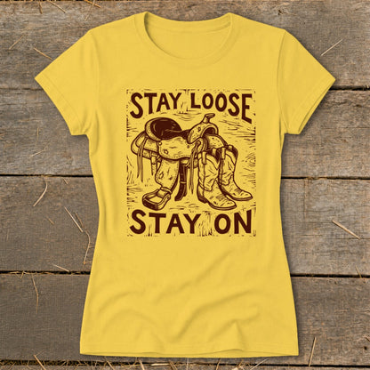 Yellow t-shirt with brown saddle, boots, and text "Stay Loose Stay On".