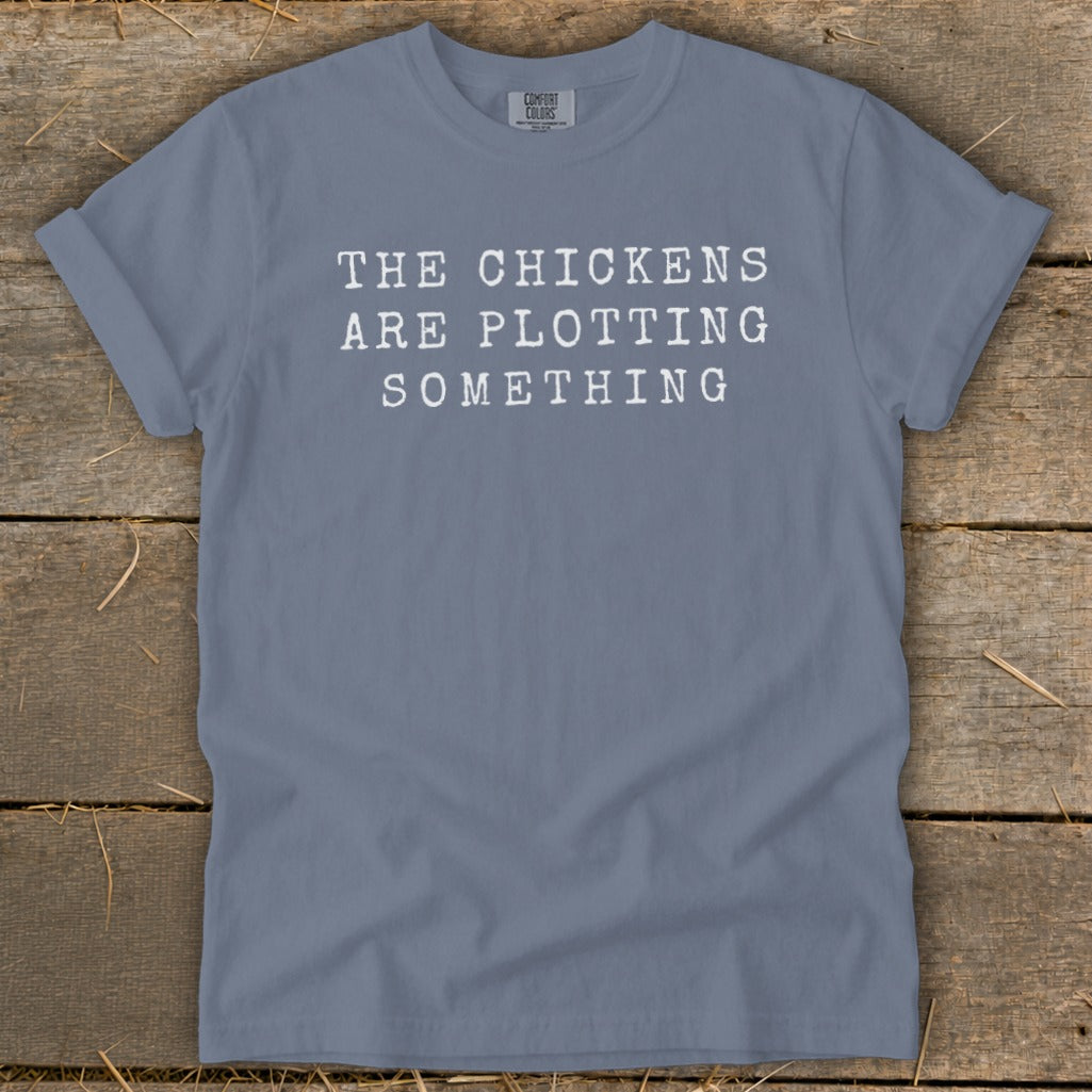 Blue t-shirt with white text reading "THE CHICKENS ARE PLOTTING SOMETHING".