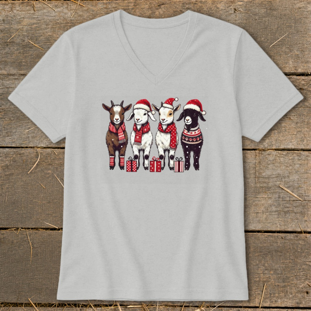 Four goats wearing Santa hats and scarves stand with Christmas gifts.