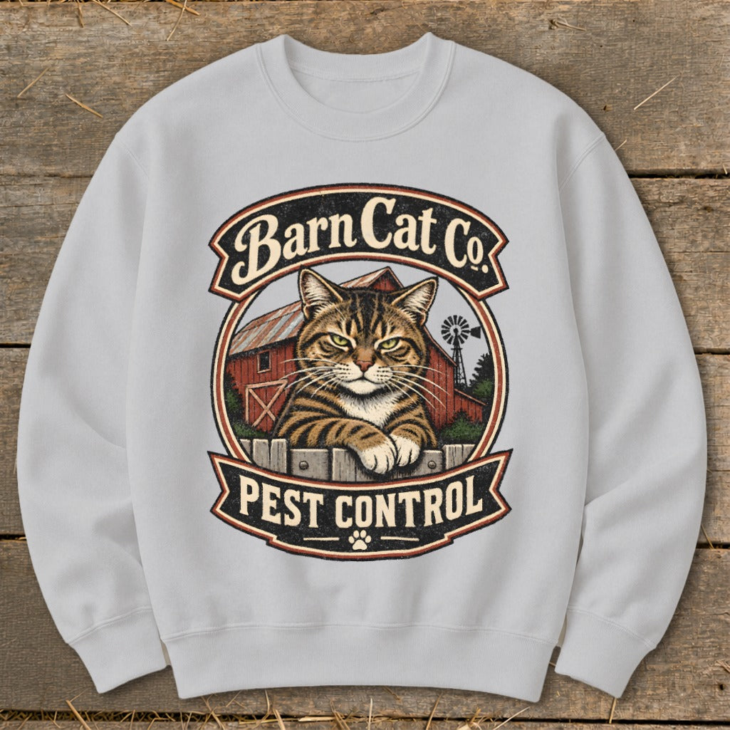 Light gray crewneck sweatshirt featuring a vintage graphic of a tabby cat resting on a fence in front of a red barn with text reading Barn Cat Co Pest Control.