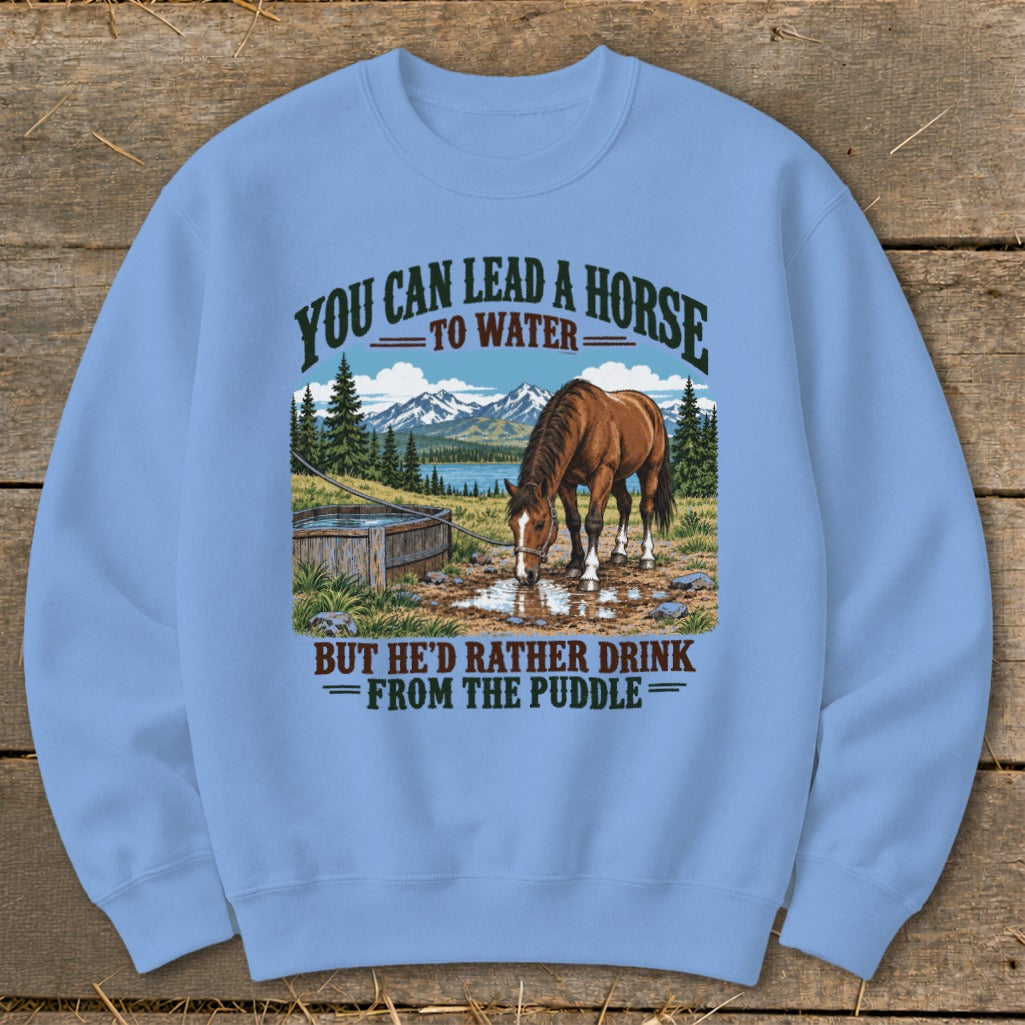 Light blue crewneck sweatshirt featuring a graphic of a horse drinking from a puddle with mountains behind it.
