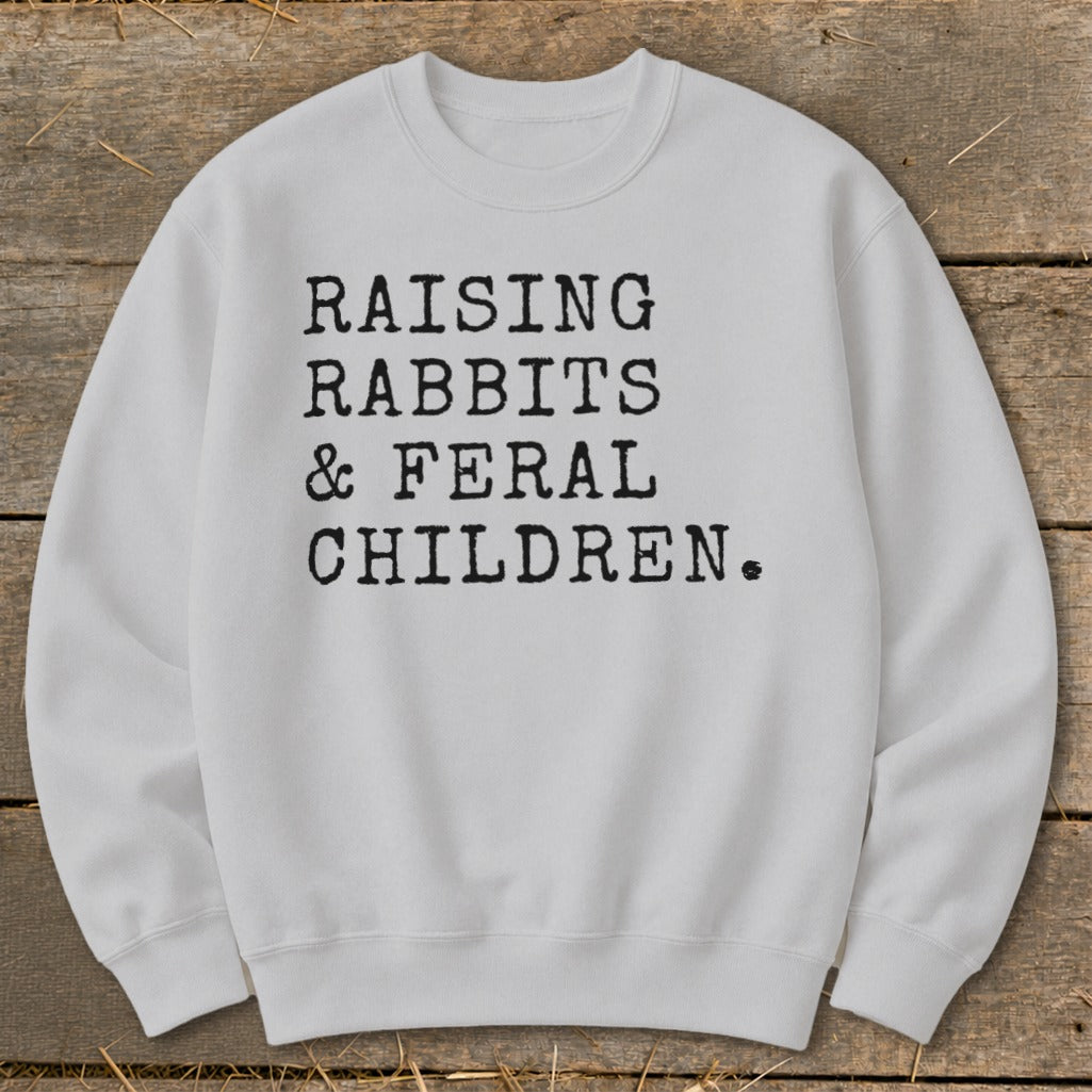 White sweatshirt with black text "Raising Rabbits & Feral Children."