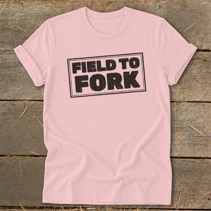 Light pink t-shirt featuring a black rectangular stamp graphic with the text FIELD TO FORK.