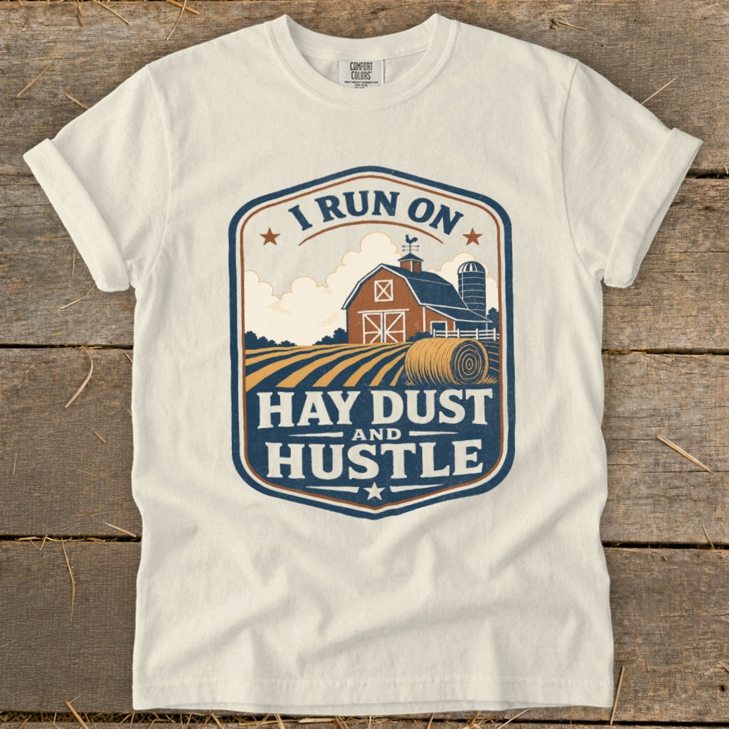 White t-shirt with a barn, silo, hay bale, and "I RUN ON HAY DUST AND HUSTLE" text.