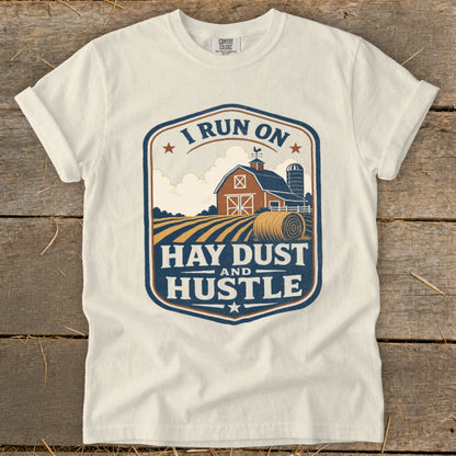 White t-shirt with a barn, silo, hay bale, and "I RUN ON HAY DUST AND HUSTLE" text.