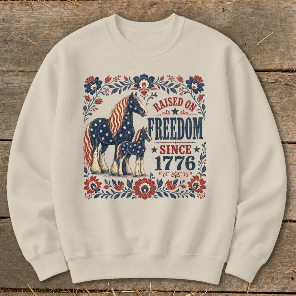 Cream sweatshirt with American flag horses and "Raised on Freedom Since 1776" text.
