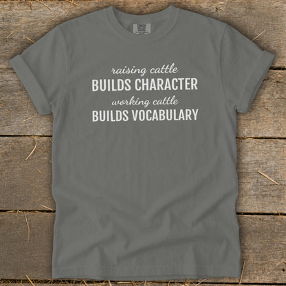 Grey t-shirt with white text: "raising cattle BUILDS CHARACTER working cattle BUILDS VOCABULARY"