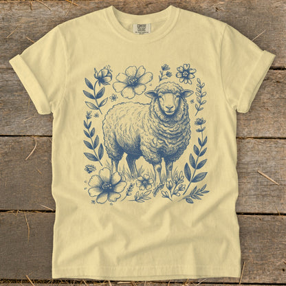 Yellow t-shirt with a blue ink drawing of a sheep surrounded by flowers and leaves.