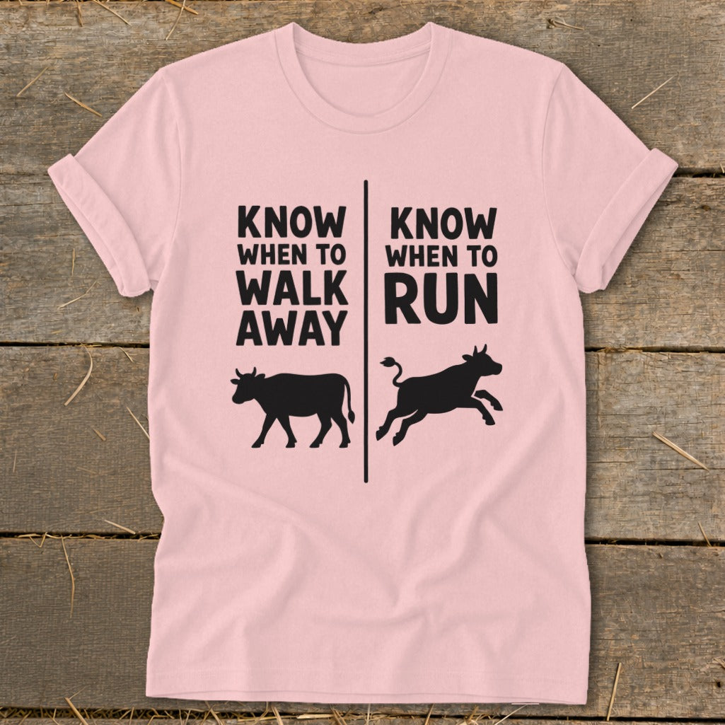 Pink t-shirt with black text "KNOW WHEN TO WALK AWAY" and a cow, and "KNOW WHEN TO RUN" and a running cow.