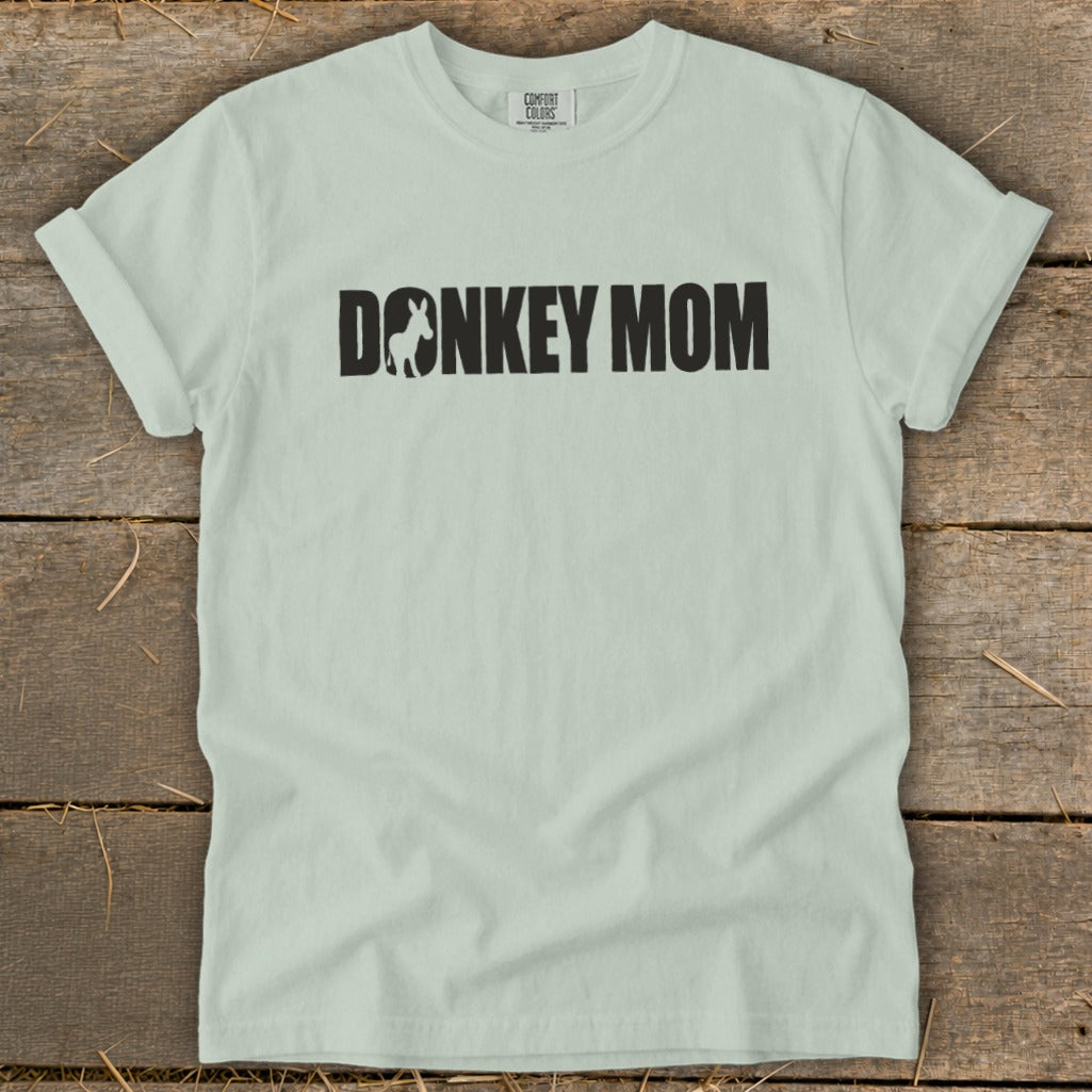 Light green t-shirt with rolled sleeves featuring the bold black text Donkey Mom on the chest.