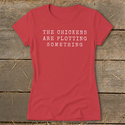 Red t-shirt with white text that reads "THE CHICKENS ARE PLOTTING SOMETHING".