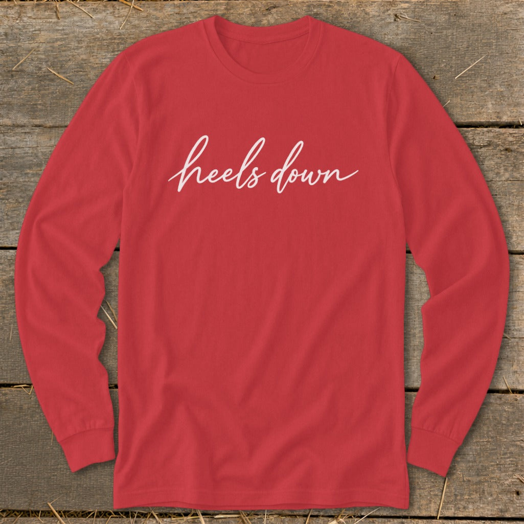 Red long-sleeve shirt with "heels down" in white script text.