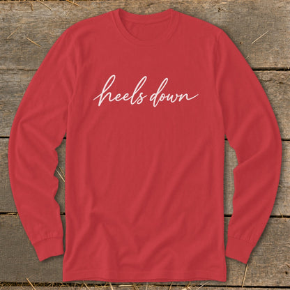 Red long-sleeve shirt with "heels down" in white script text.