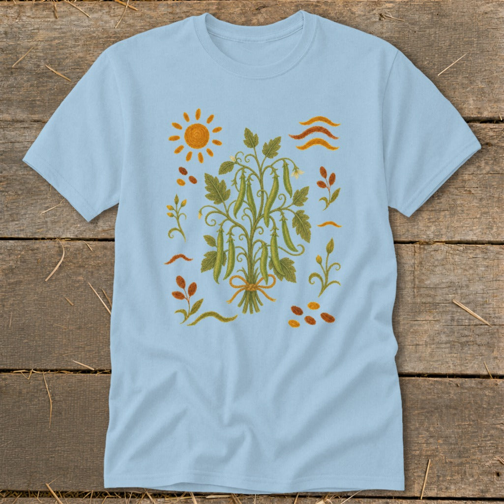 Light blue t-shirt with a central embroidered design of pea pods on a vine, sun, and leaves.