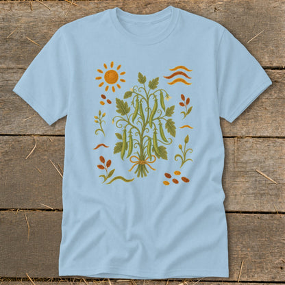 Light blue t-shirt with a central embroidered design of pea pods on a vine, sun, and leaves.