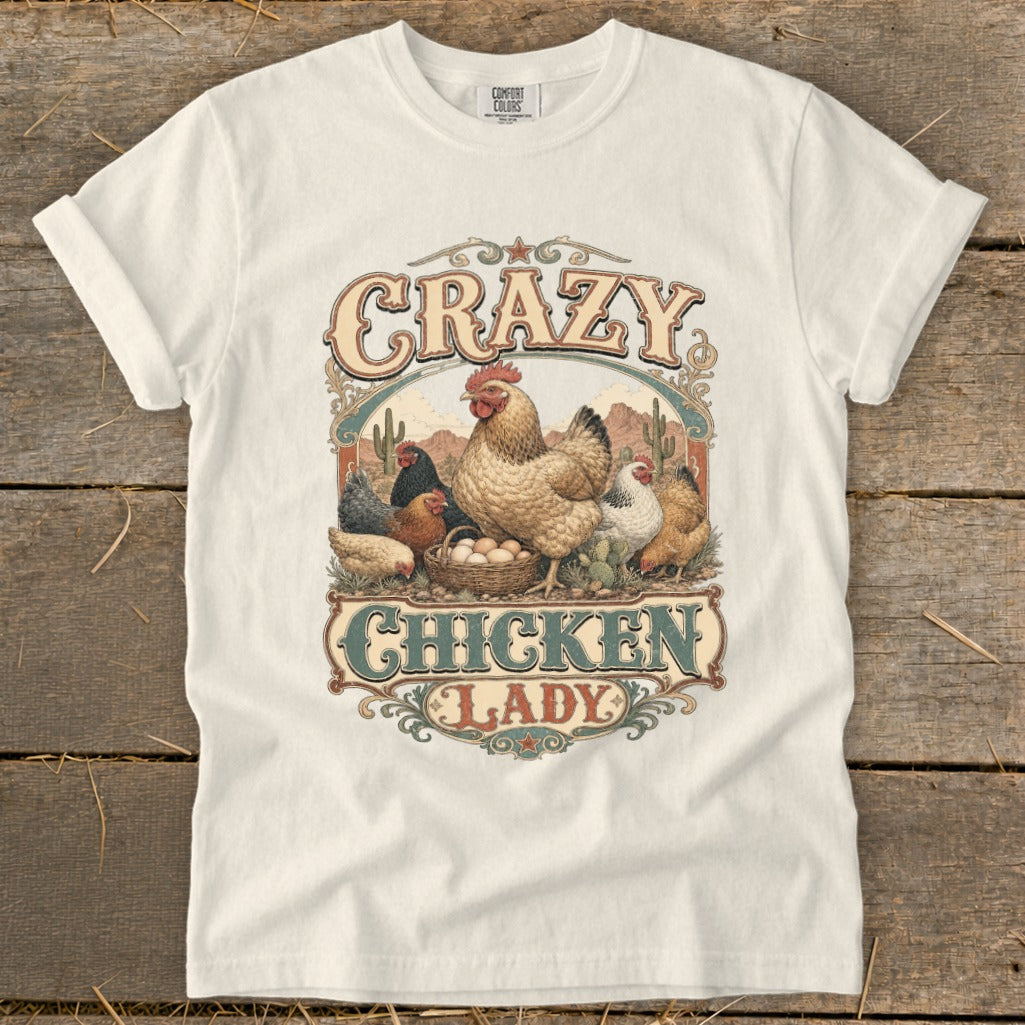 White t-shirt graphic with "Crazy Chicken Lady" text and illustrated chickens in desert landscape.