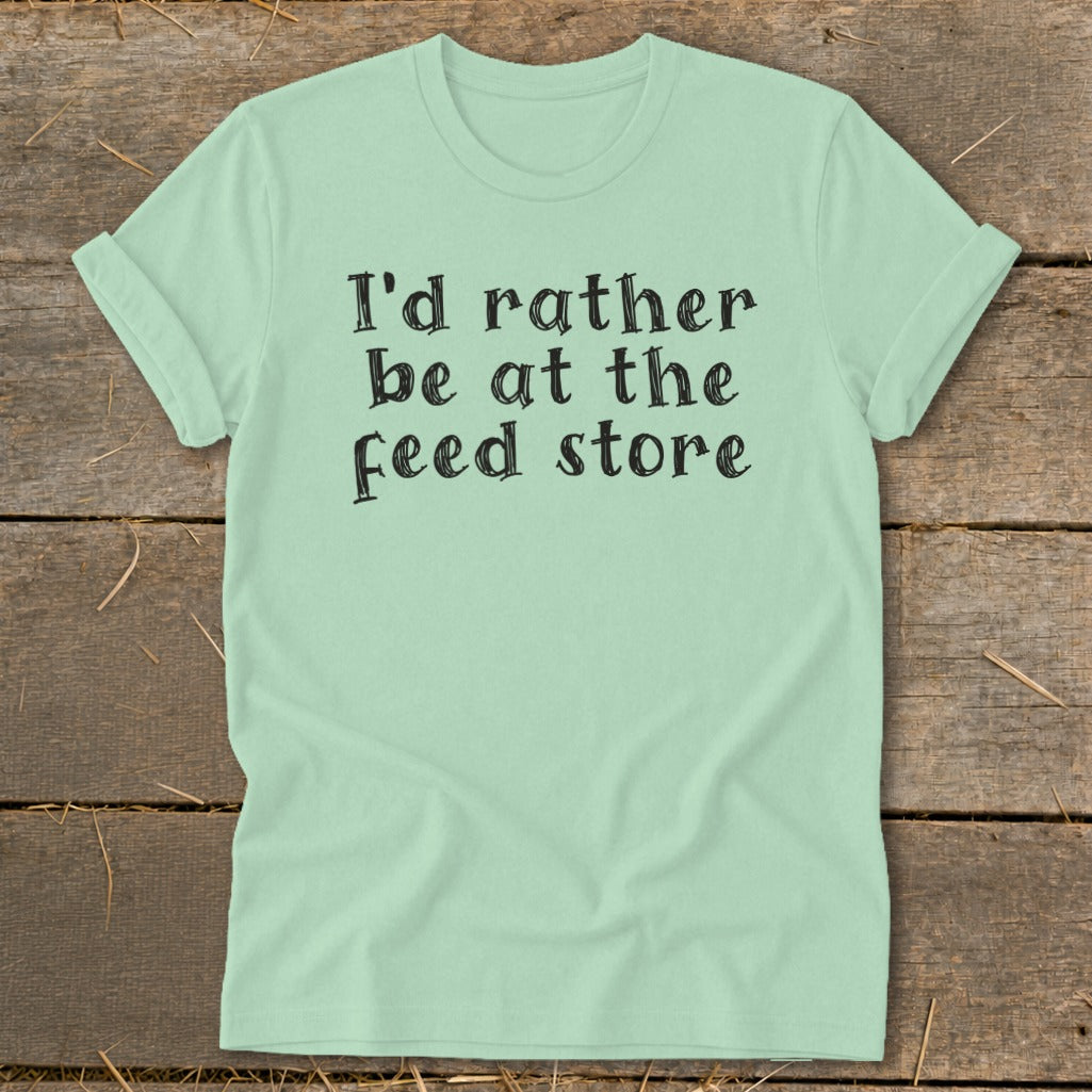 Light mint t-shirt with black text that reads "I'd rather be at the feed store".