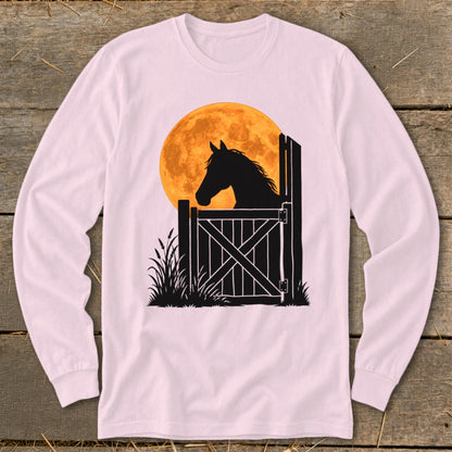 Light pink long-sleeve t-shirt featuring a black silhouette of a horse looking over a gate against a large orange moon.