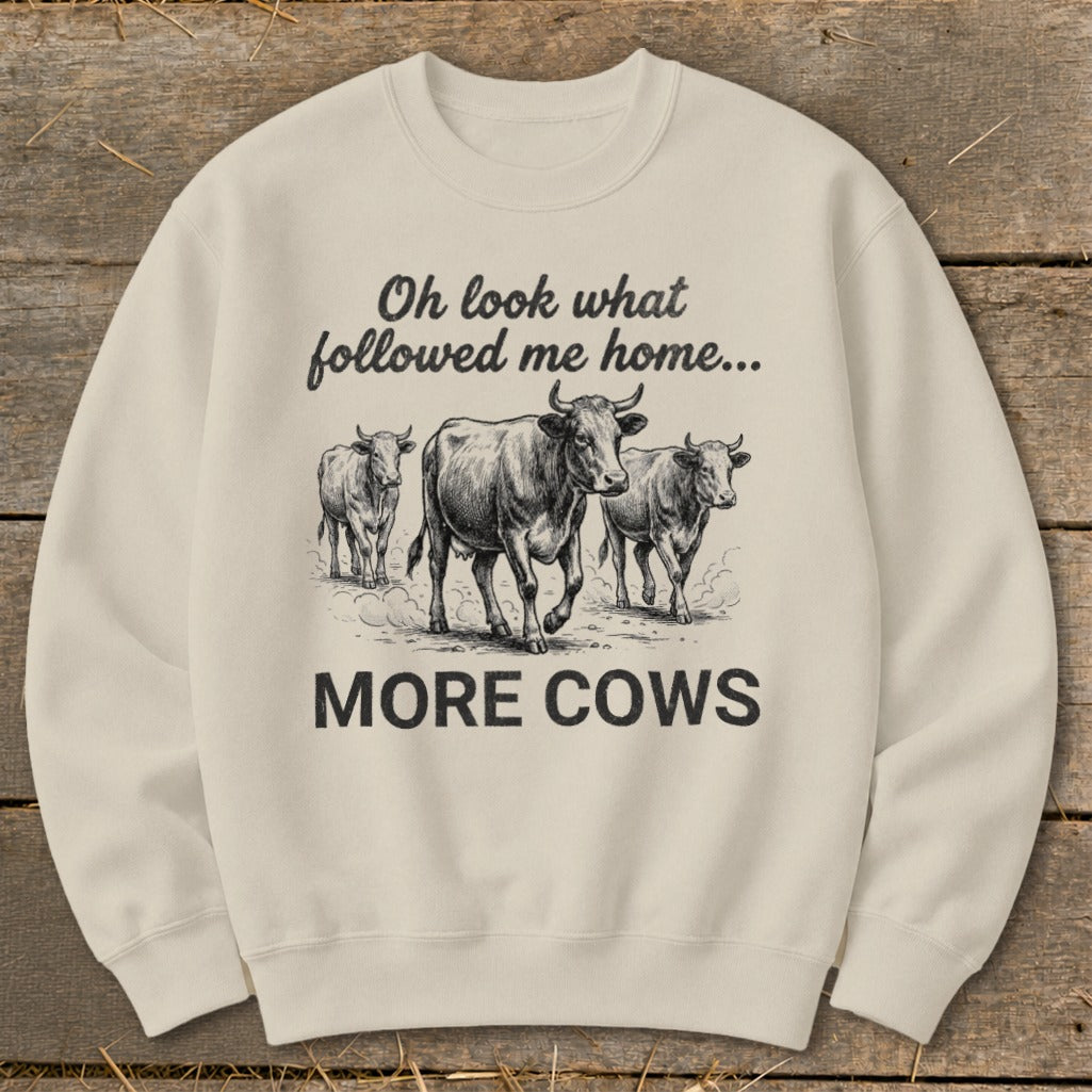 Cream sweatshirt with black graphic of cows and text "Oh look what followed me home... MORE COWS."