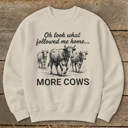 Cream sweatshirt with black graphic of cows and text "Oh look what followed me home... MORE COWS."