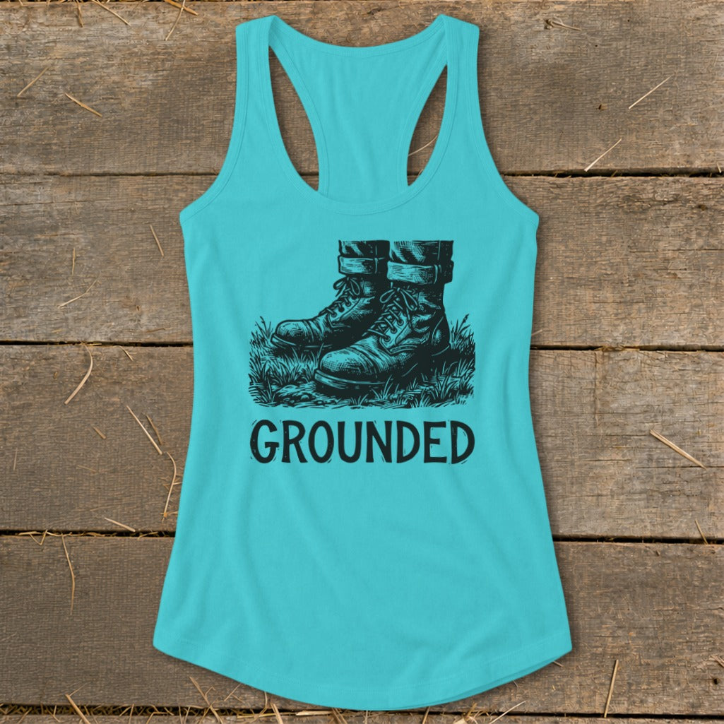 Turquoise tank top with a graphic of boots in grass and the word "GROUNDED".