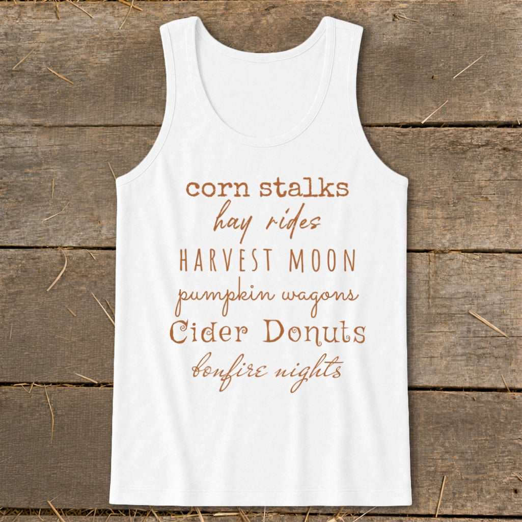 White tank top with text listing fall activities: corn stalks, hay rides, harvest moon, pumpkin wagons, cider donuts, bonfire nights.