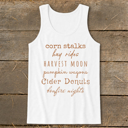 White tank top with text listing fall activities: corn stalks, hay rides, harvest moon, pumpkin wagons, cider donuts, bonfire nights.