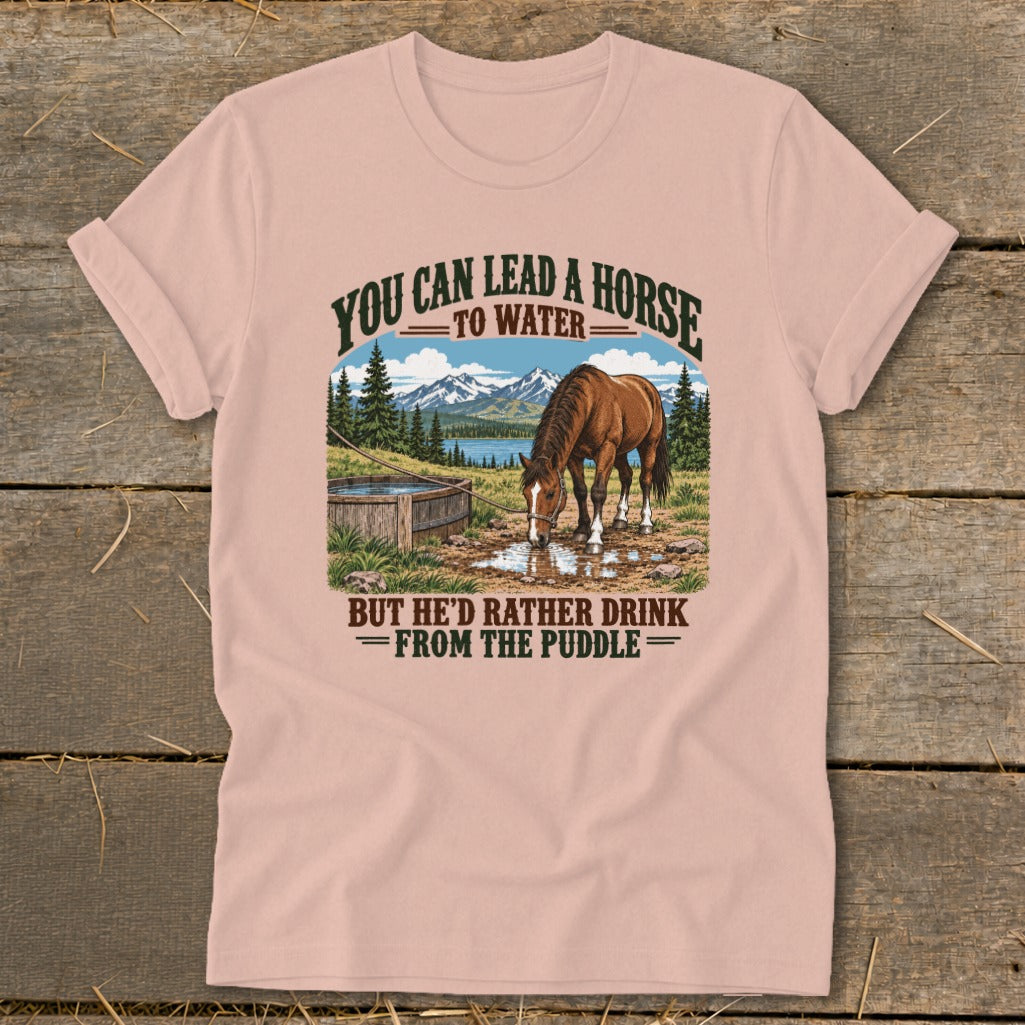 Dusty pink t-shirt with a vintage graphic of a horse drinking from a puddle, flanked by mountains and text.