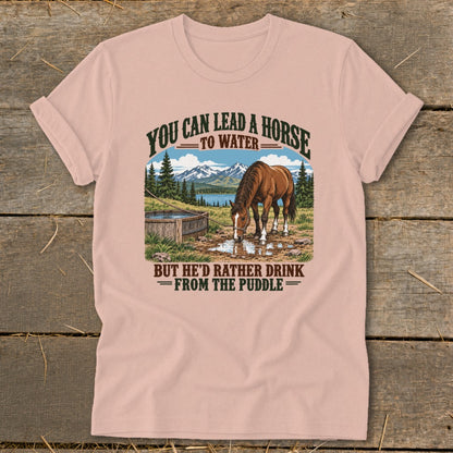 Dusty pink t-shirt with a vintage graphic of a horse drinking from a puddle, flanked by mountains and text.