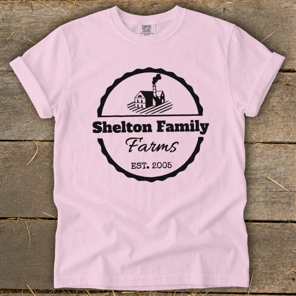 Pink t-shirt with black Shelton Family Farms logo, featuring a house and EST. 2005.
