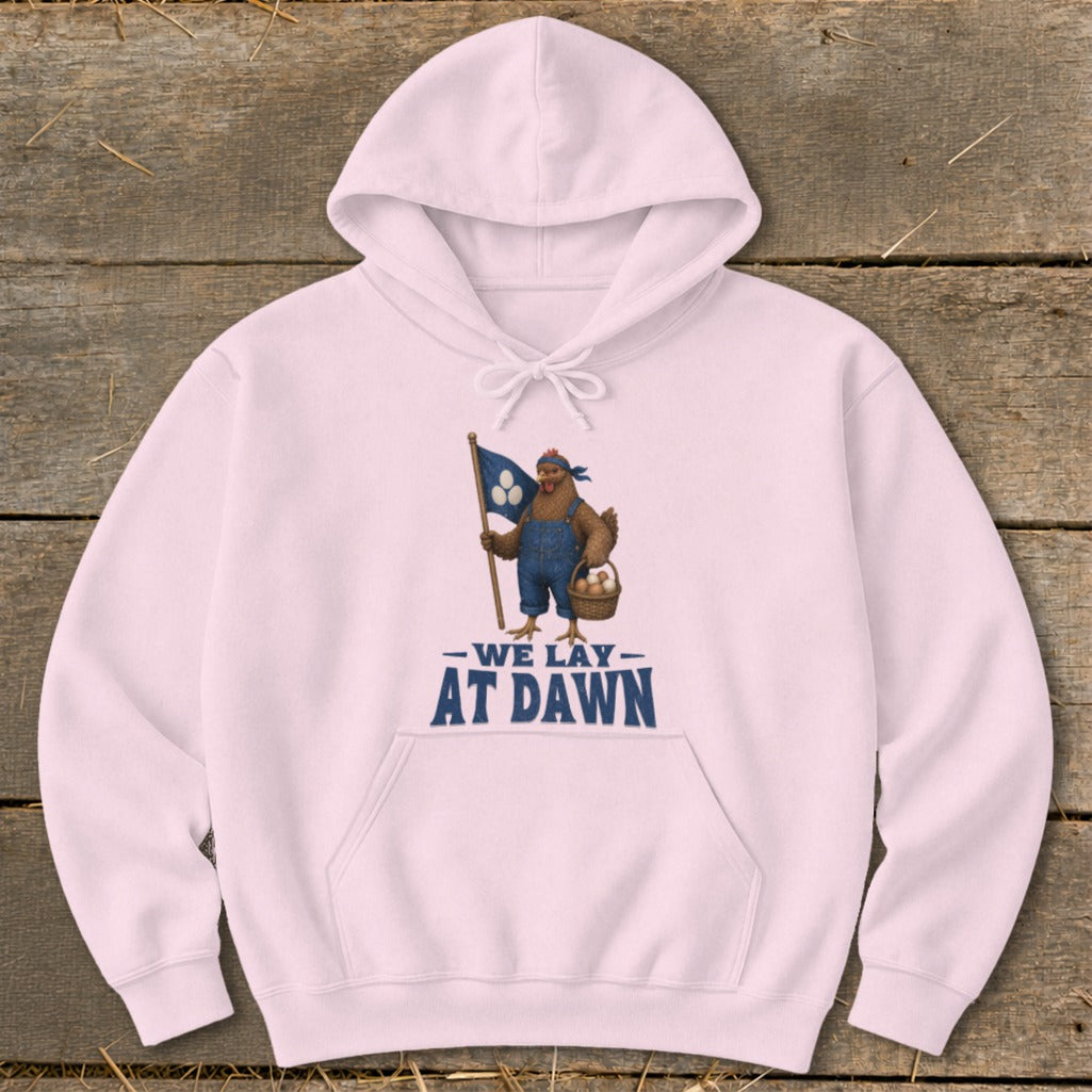 Pink hoodie with chicken graphic holding a flag and basket of eggs, text "WE LAY AT DAWN".