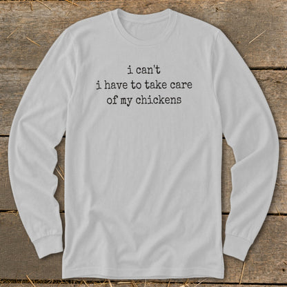 White long-sleeve t-shirt with black text that says "i can't i have to take care of my chickens".