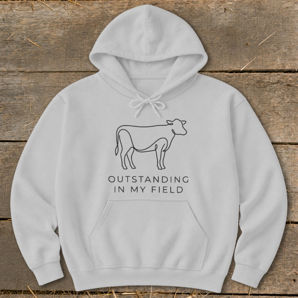 White hoodie with line art cow and text "Outstanding in my field".