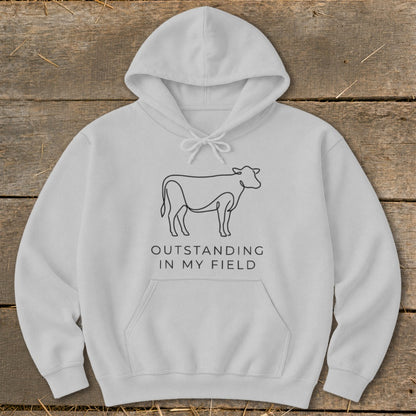 White hoodie with line art cow and text "Outstanding in my field".