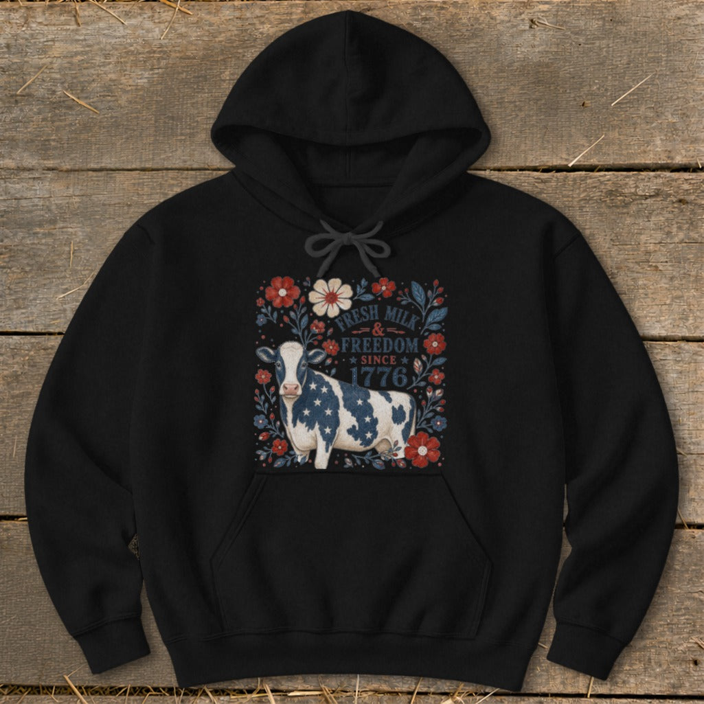 Black hoodie with a cow on a rustic wood background.