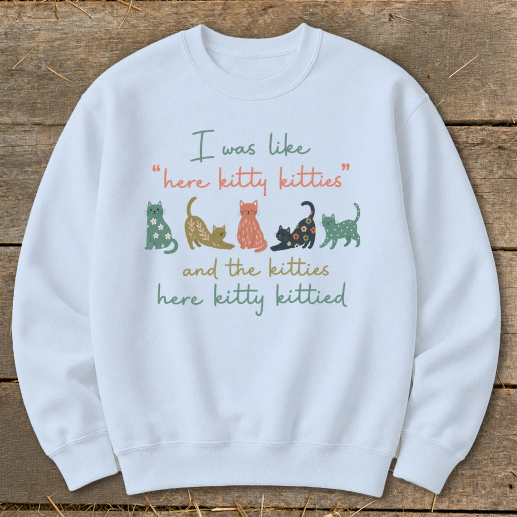 White sweatshirt with graphic of cats and text "I was like 'here kitty kitties' and the kitties here kitty kittied".