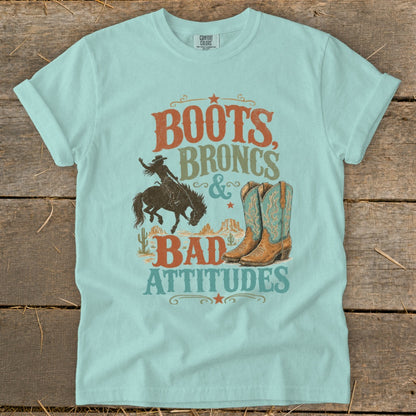 Light blue t-shirt with text: Boots, Broncs & Bad Attitudes, cowboy, and boots graphic.