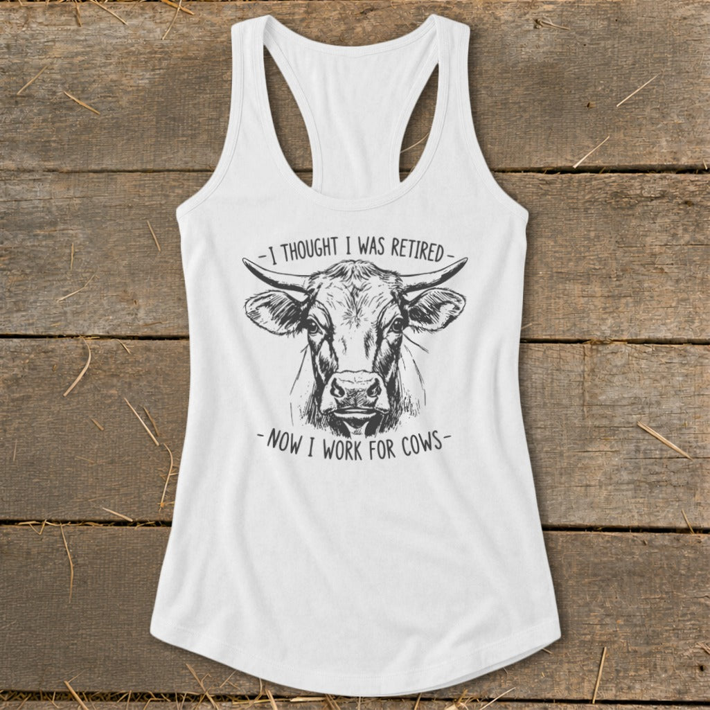 White tank top with black sketch of cow and text "-I THOUGHT I WAS RETIRED- -NOW I WORK FOR COWS-".