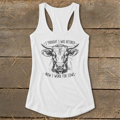 White tank top with black sketch of cow and text "-I THOUGHT I WAS RETIRED- -NOW I WORK FOR COWS-".