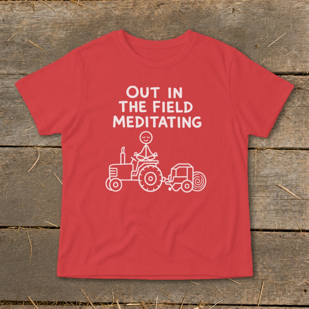Red t-shirt with white text and graphic of stick figure meditating on a tractor baling hay.