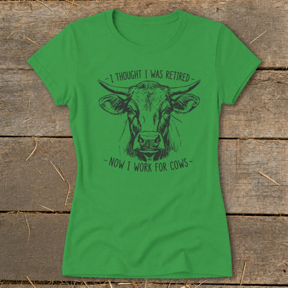 Green t-shirt with a cow illustration and text "I thought I was retired - Now I work for cows".