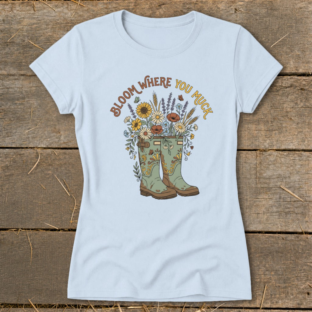 Light blue t-shirt with green boots and flowers graphic reading "Bloom Where You Muck."