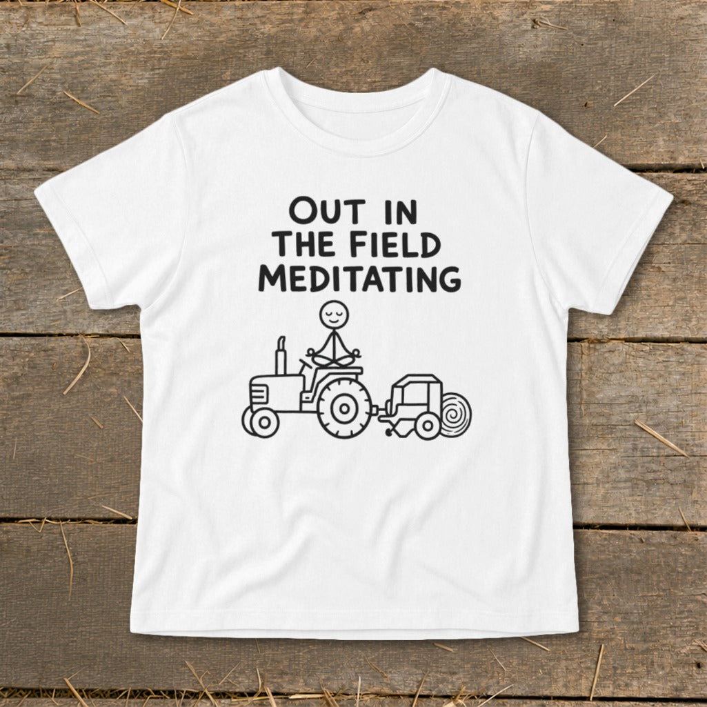 White t-shirt with "OUT IN THE FIELD MEDITATING" and stick figure on tractor.