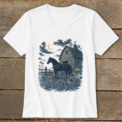 Dark horse stands in field with barn and moon at night.