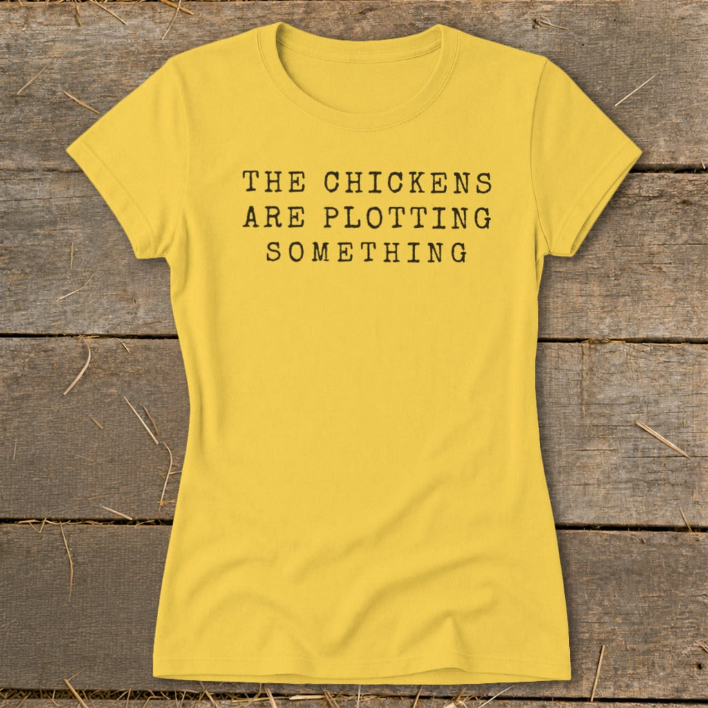 Yellow t-shirt with black text reading "The Chickens Are Plotting Something".